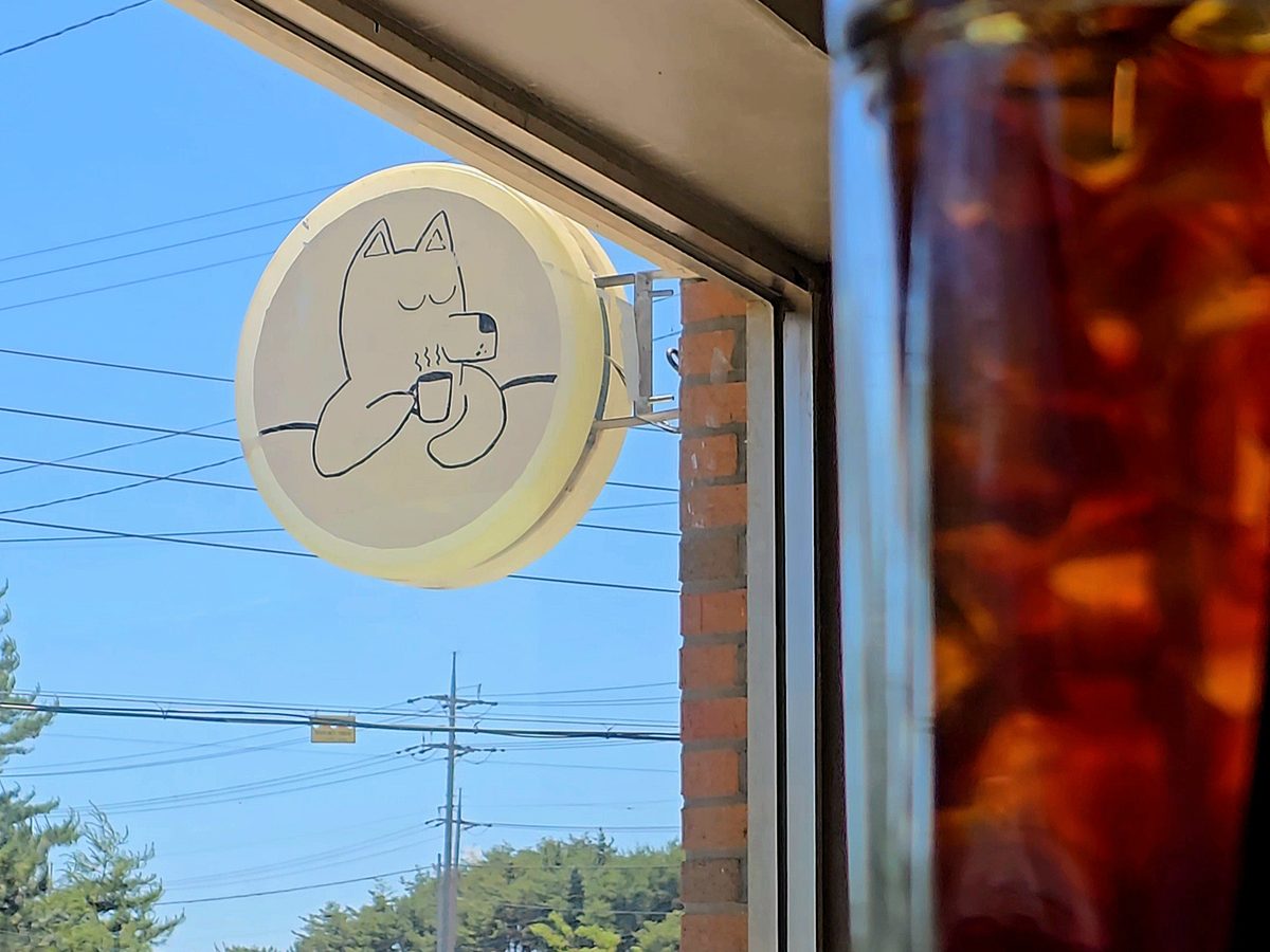 파란 하늘 아래 가게 벽에 걸린 커피 마시는 뭉개 간판